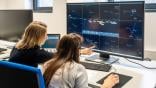 people looking at data on a monitor