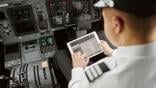 pilot looking at an iPad in the cockpit of an airplane